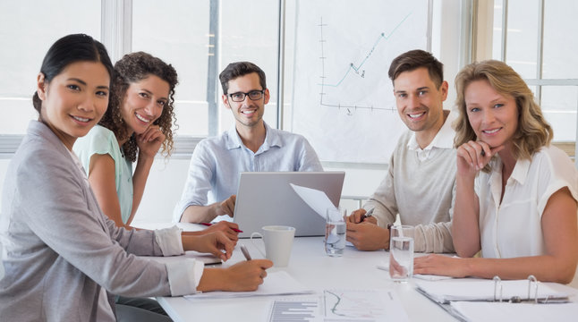 Casual business team having a meeting smiling at camera