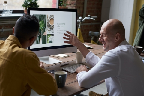 Two people sitting in front of a computer talking