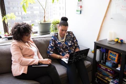 Coworkers sitting on a couch looking at laptop