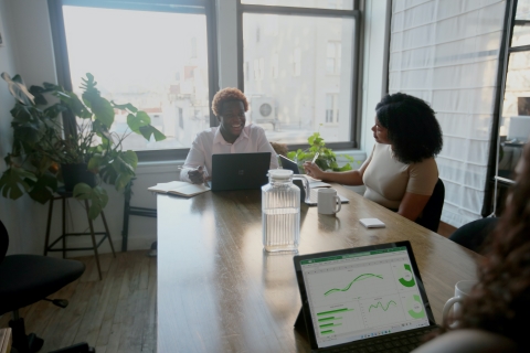 Coworkers sitting around a conference table with laptops smiling