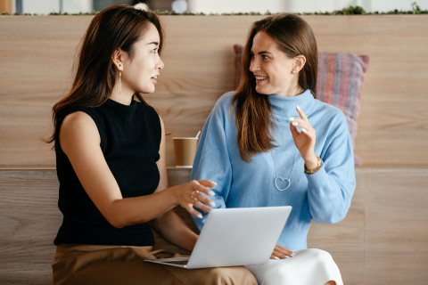 Two people sitting and talking while moving their hands