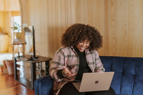 person looking and smiling at her laptop screen