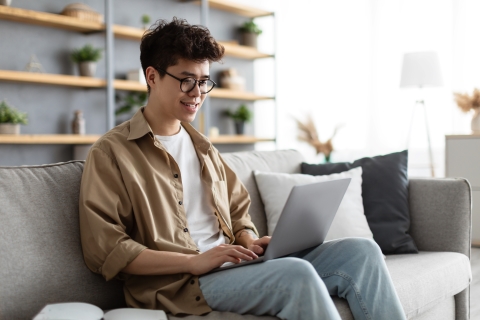 Person sitting on a couch typing on a laptop on their lap